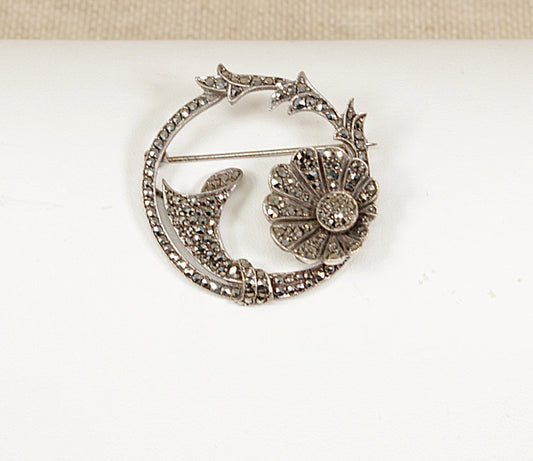 Decorative silver and marcasite art nouveau brooch with floral design on a white background 