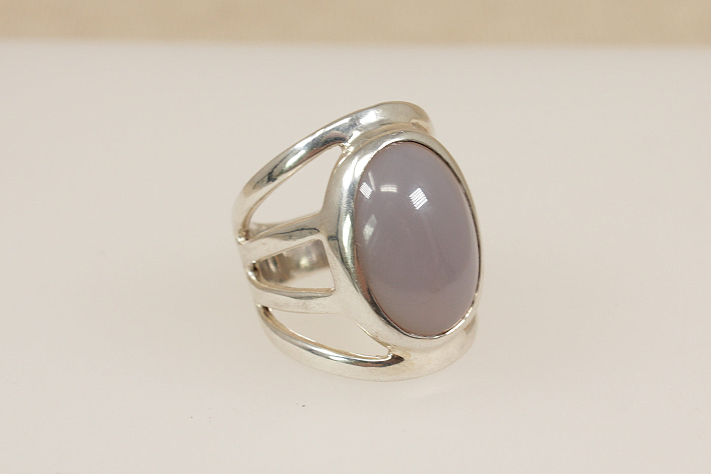 Silver ring with a pink stone on a beige background