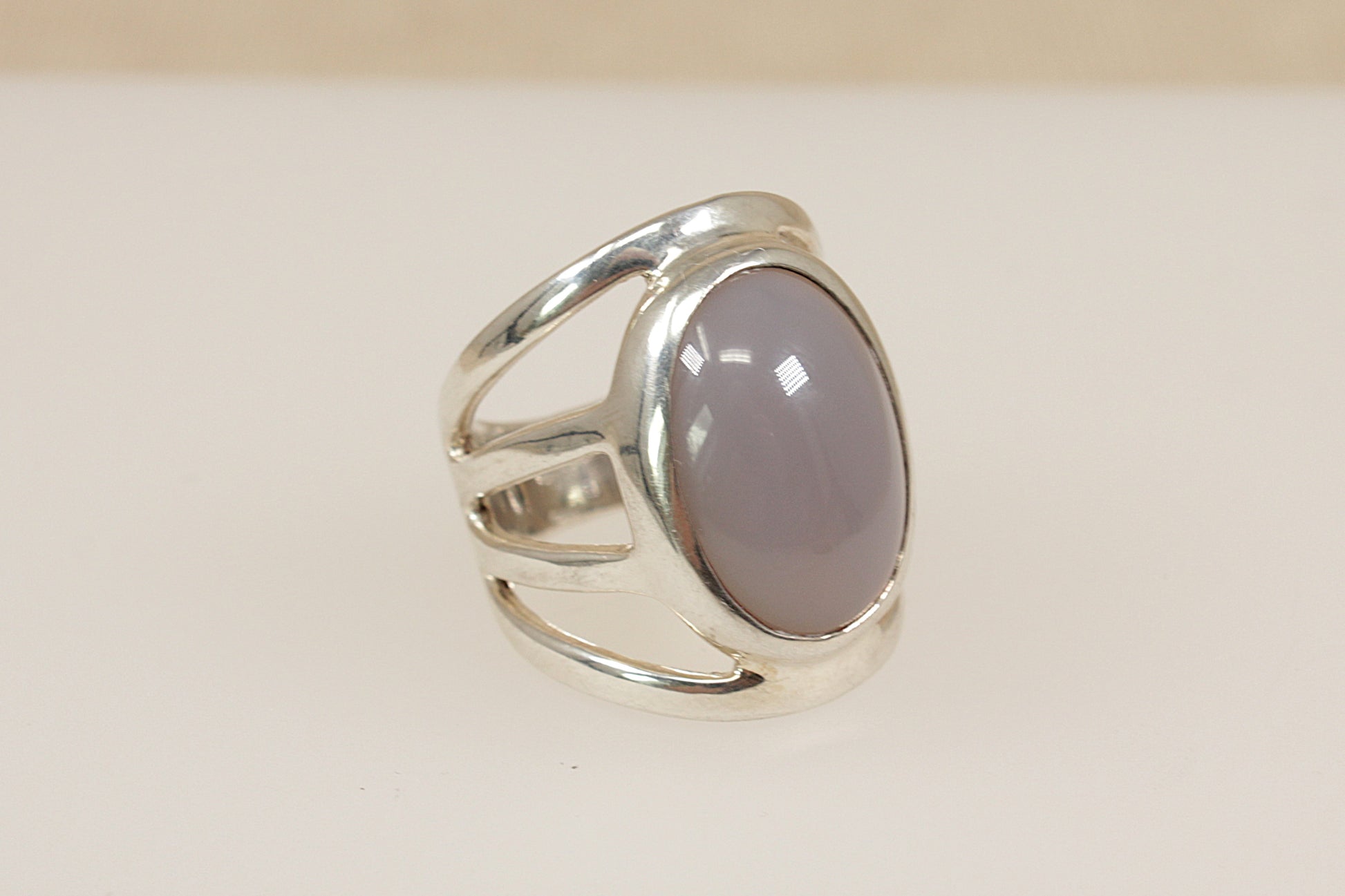 Silver ring with a pink stone on a beige background