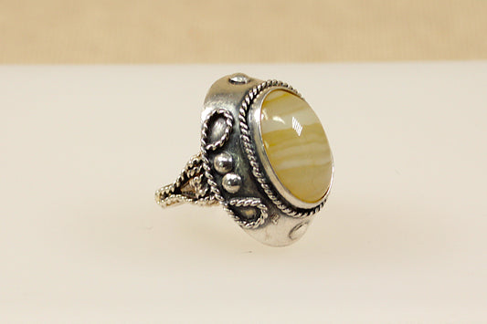 A vintage silver ring with an oval banded agate stone set in an ornate silver setting with polish Continental silver hallmarks.