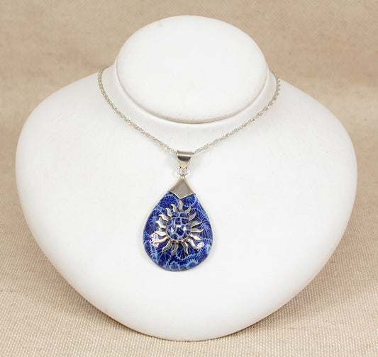 Necklace with a blue teardrop pendant on a white stand against a beige background