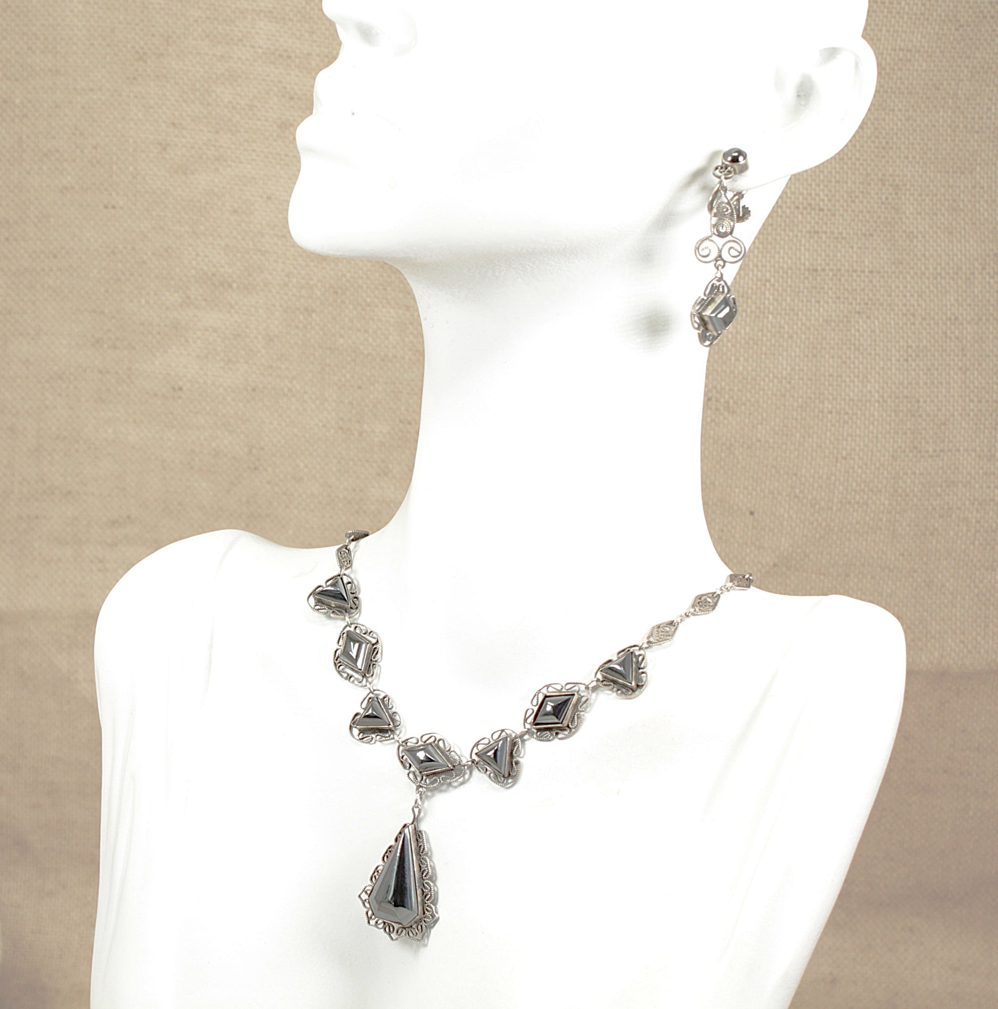 Vintage silver hematite necklace and earrings on a mannequin with a beige background