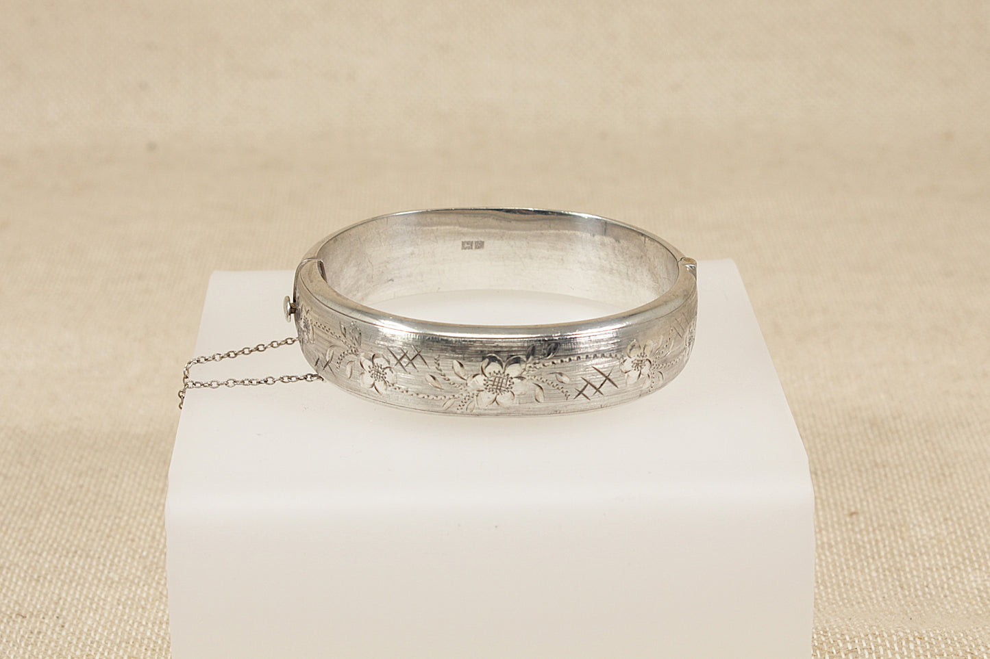 Vintage Antique Silver bracelet bangle  on a white cube with a beige background