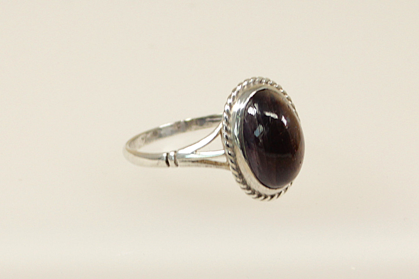 A silver ring with a large cabochon iolite gemstone, showcasing an oval shape with a deep indigo color, set in a handcrafted band with hallmarks for 1991.