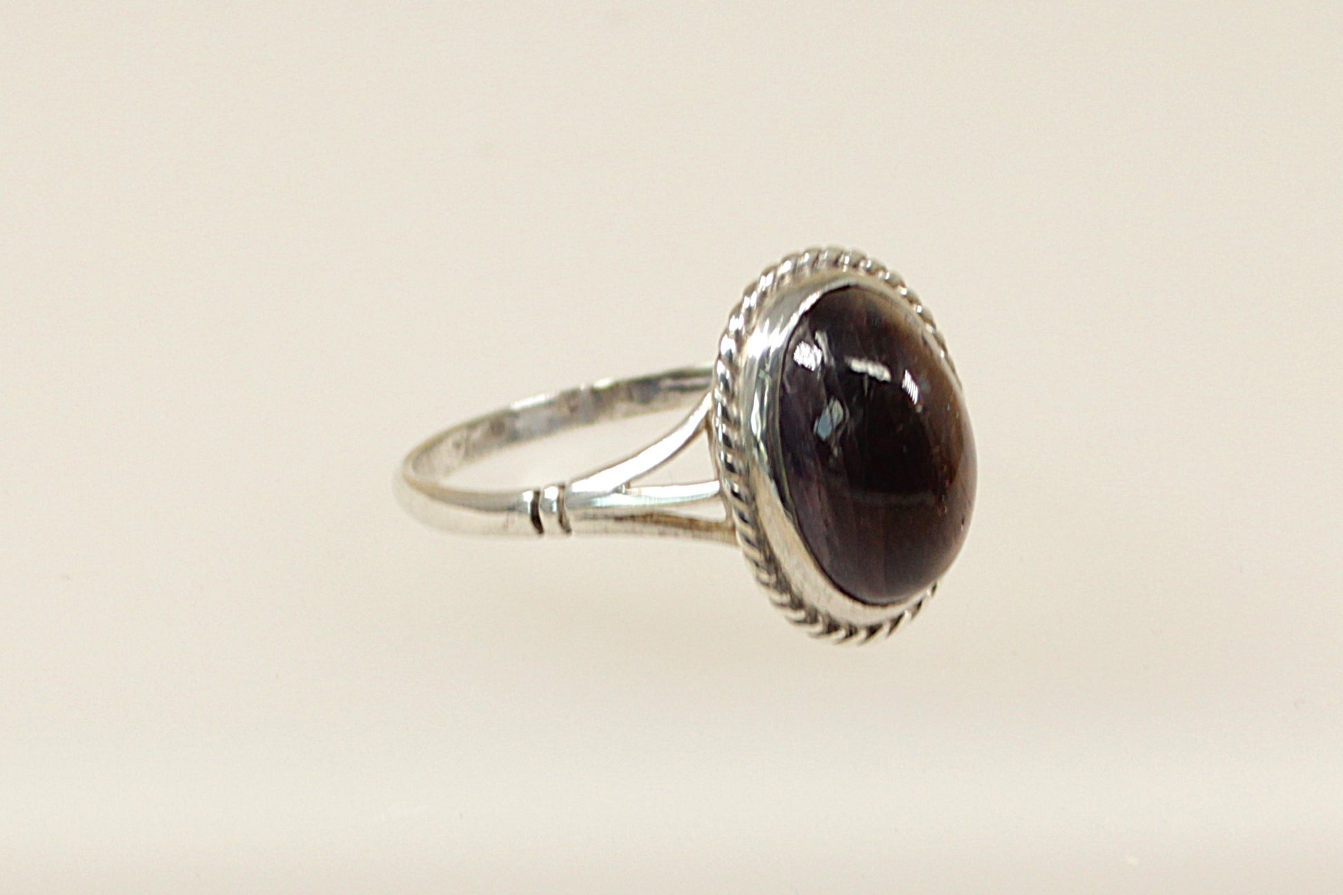 A silver ring with a large cabochon iolite gemstone, showcasing an oval shape with a deep indigo color, set in a handcrafted band with hallmarks for 1991.
