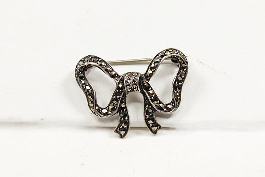 Decorative bow-shaped brooch with marcasite gemstones on a white background