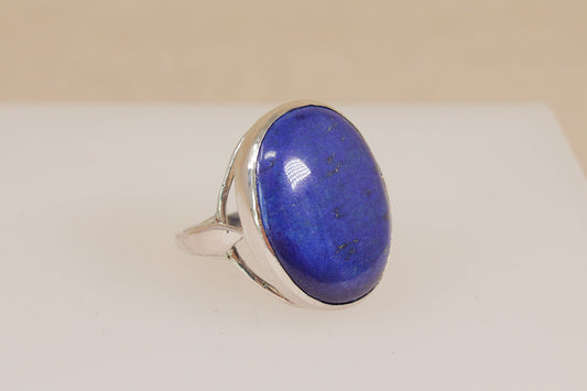 Statement Ring with a blue lapis lazuli gemstone and silver band on a beige background